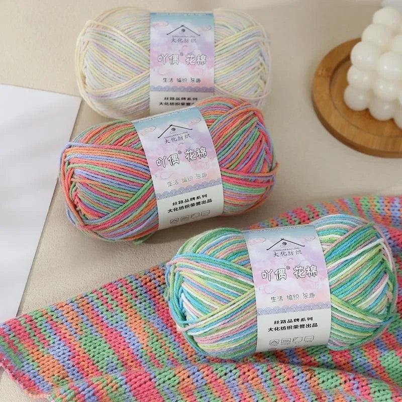 Three skeins of multicolored 4-ply cotton knit yarn displayed on a light surface.