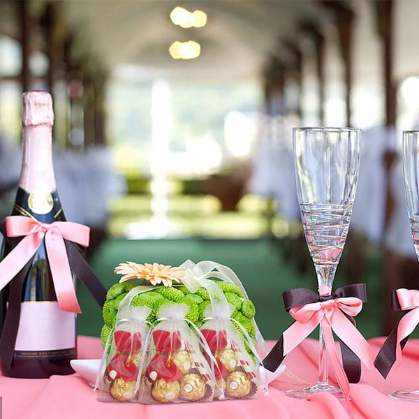 Pink organza gift bags filled with gold jewelry and candy displayed on a table.