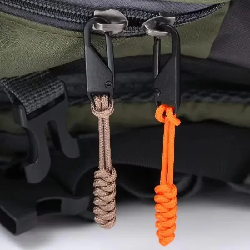 Two detachable zipper pull sliders in gray and orange are shown attached to a dark green fabric bag.