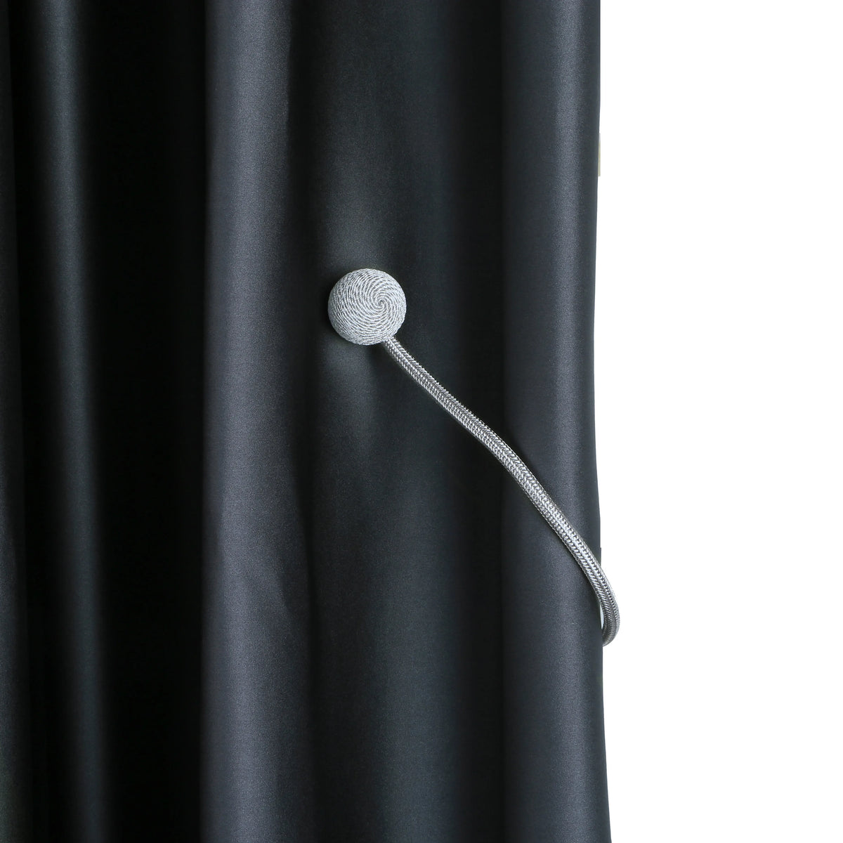 Silver magnetic curtain tieback attached to a dark gray fabric curtain.
