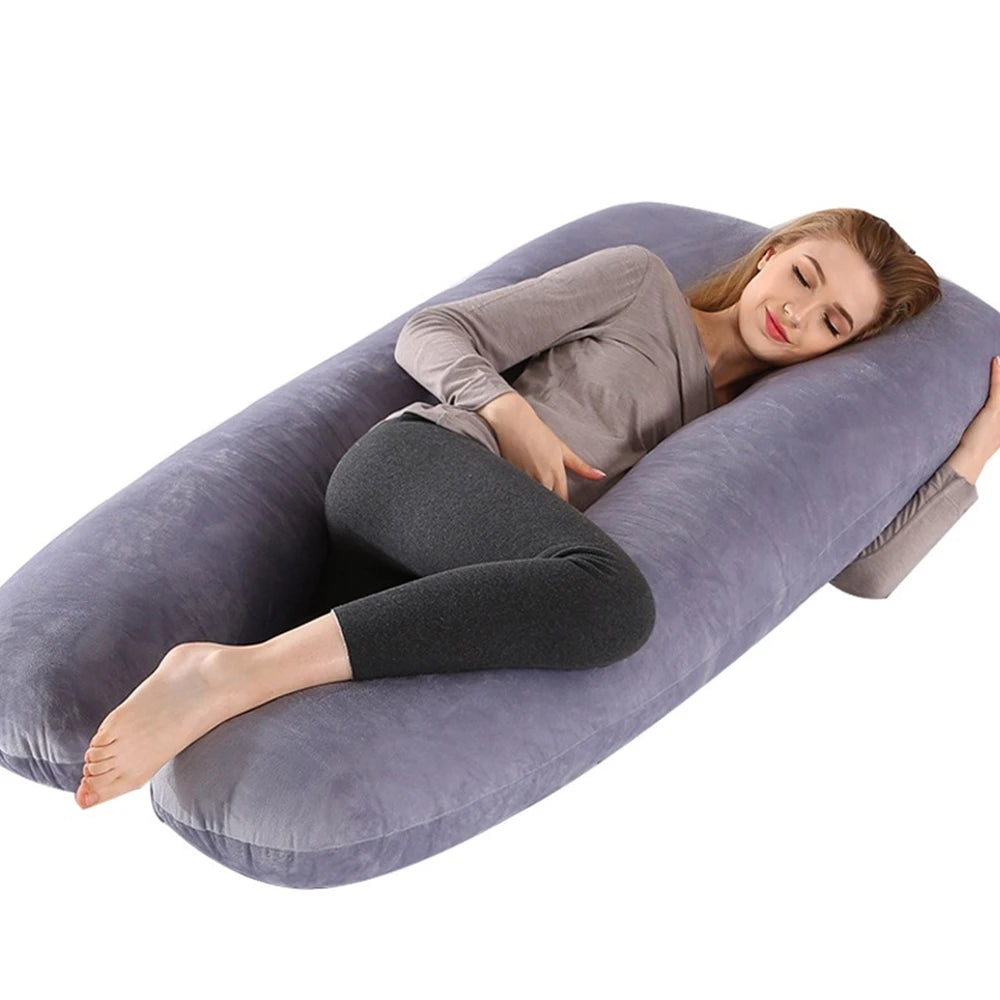 A woman is lying on a gray U-shaped maternity body pillow.