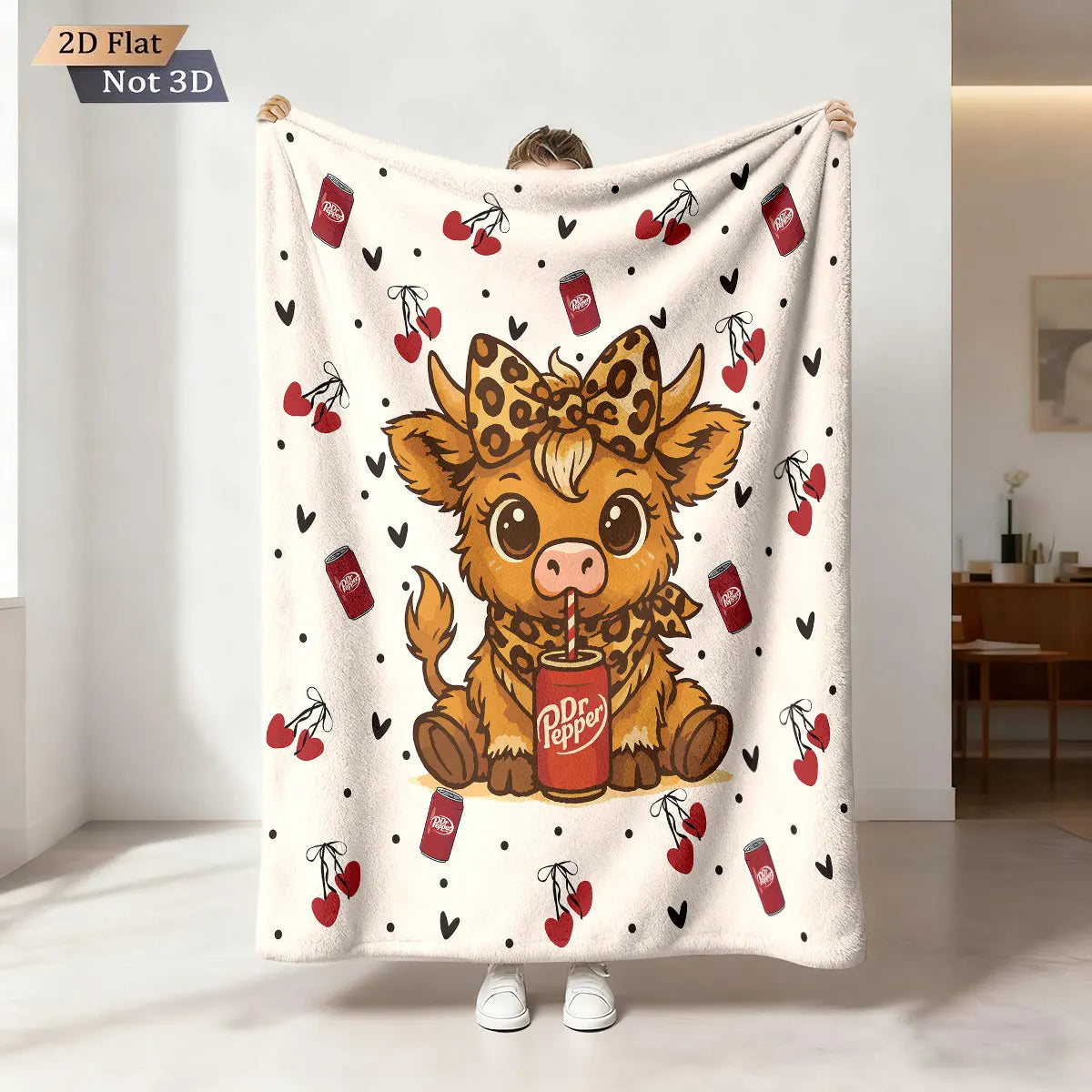 A cream-colored flannel blanket featuring a cartoon Highland cow print with red berries and a red can.