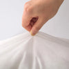 A hand is adjusting a white soft cotton-padded headboard cushion fabric.