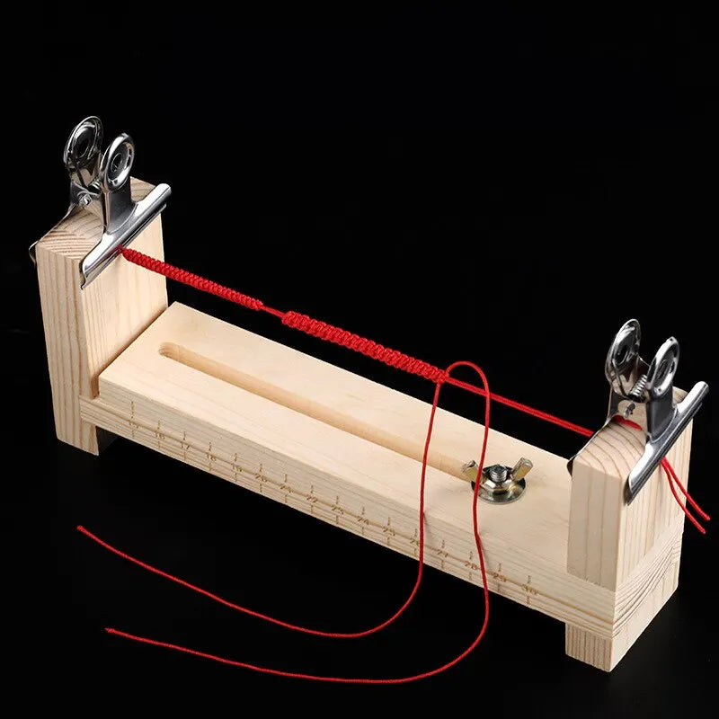 A wooden braiding frame with red strings and metal clasps used for DIY bracelet making.