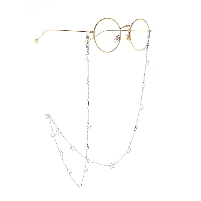 Gold-rimmed round eyeglasses with a delicate silver chain featuring small star and moon charms