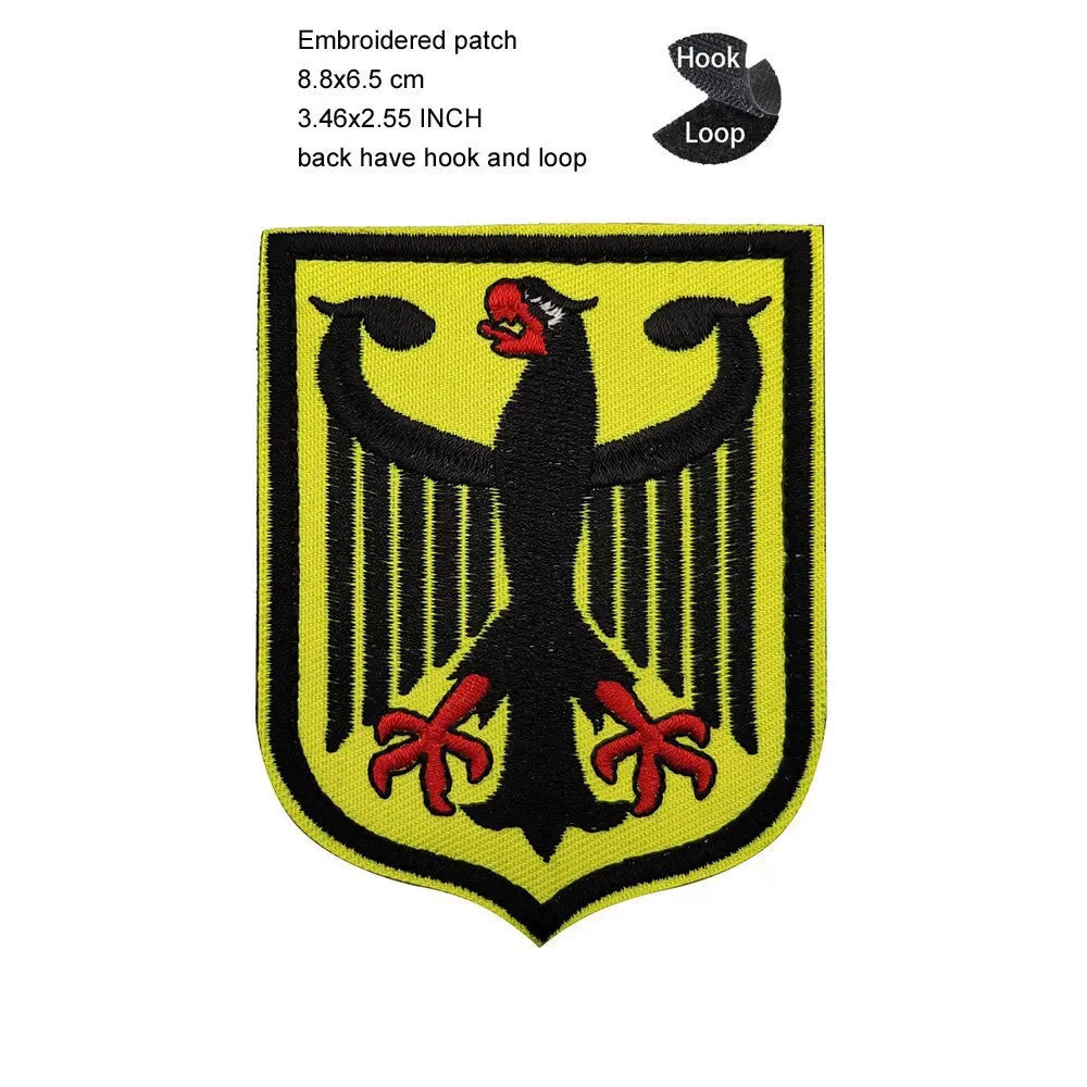 A black and yellow embroidered patch shaped like an eagle shield with a prominent beak and spread wings.