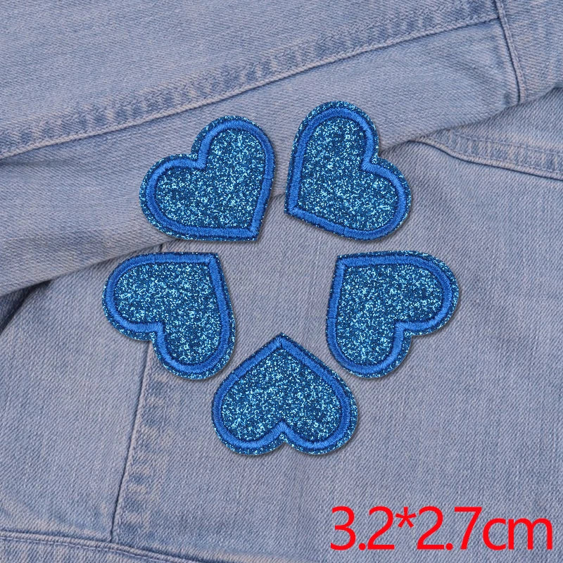 Five blue glitter heart patches embroidered on a denim fabric