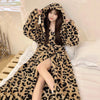 A woman wearing a beige and black leopard print flannel kimono robe indoors.