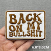 A brown embroidered patch with the text BACK ON MY BULLSHIT on a white background