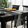 Black and gold abstract marble linen table runner displayed on a dark wooden table.
