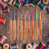 A set of bamboo knitting and crochet needles in various sizes and colors laid out on a wooden surface.