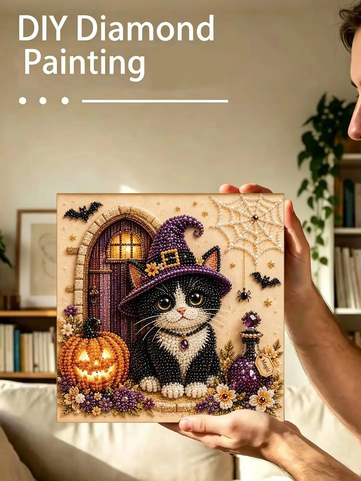 A person holds a finished diamond painting featuring a purple cat and an orange pumpkin on a framed canvas.