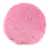 A round pink faux fur sheepskin area rug with a fluffy texture.