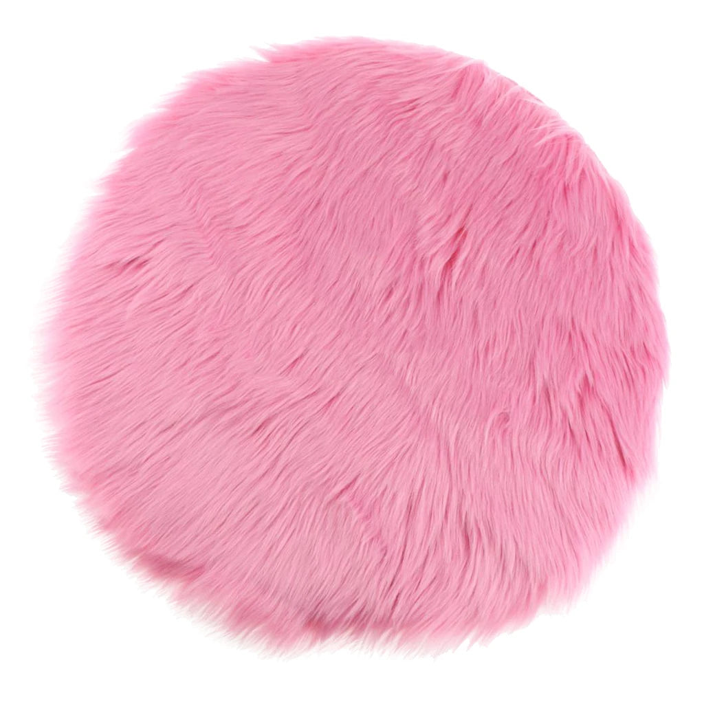 A round pink faux fur sheepskin area rug with a fluffy texture.