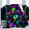 A colorful mushroom flannel throw blanket draped over a dark gray sofa.