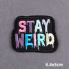 Black embroidery patch with the text STAY WEIRD in multi-colored, dripping font.