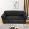 A dark gray stretch knit sofa cover with a bubble lattice texture displayed on a light rug.