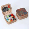A tan storage box with a lid containing various sewing needles and tools.