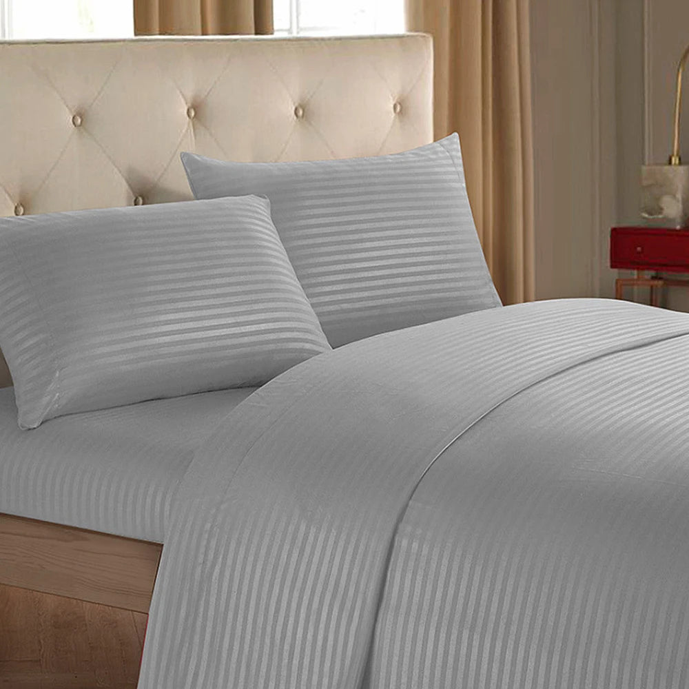 A close-up of a luxury solid stripe bedding set featuring light gray striped sheets and pillows on a bed.