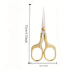 A pair of vintage stainless steel sewing scissors with gold-colored handles and a sharp blade.
