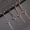 A collection of ten small, gold-toned metal lapel clips arranged on a dark surface.
