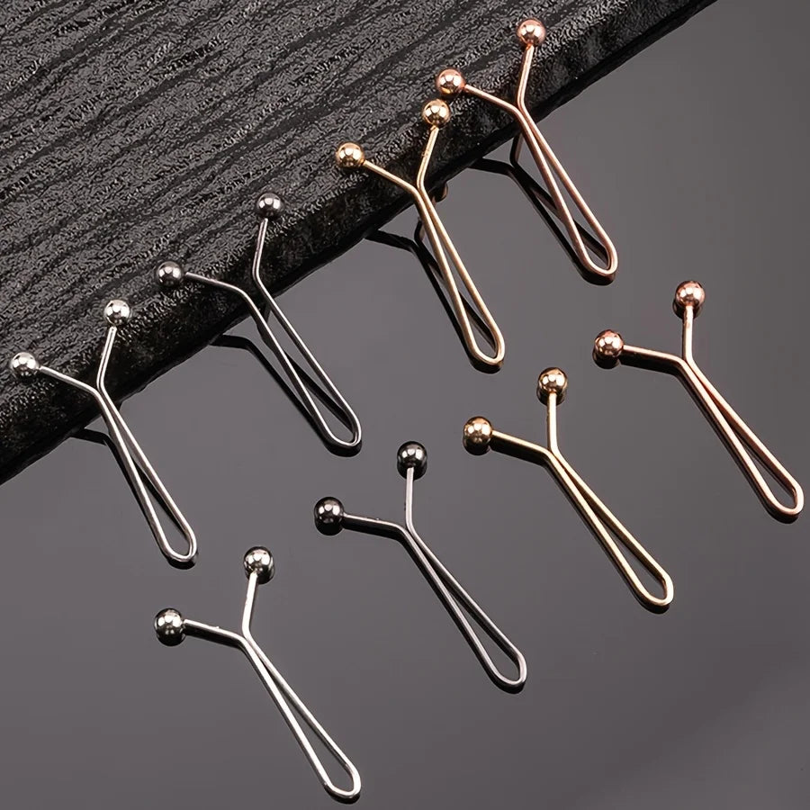 A collection of ten small, gold-toned metal lapel clips arranged on a dark surface.