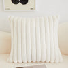 A white, ribbed plush winter throw pillow cover displayed on a light-colored sofa.