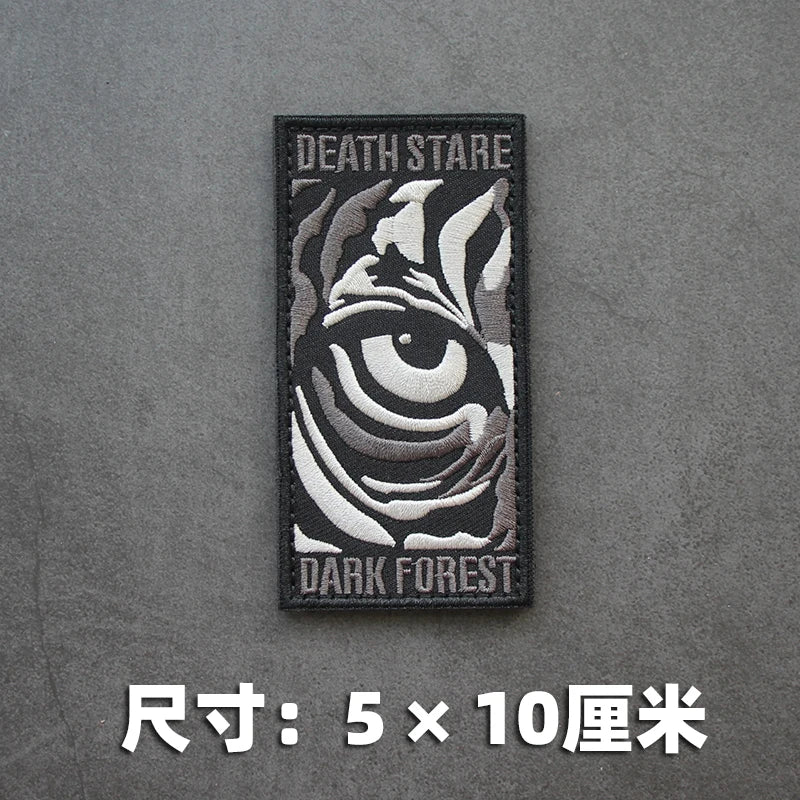 A black embroidered patch featuring a stylized tiger eye design with the text DEATH STARE and DARK FOREST.