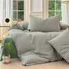 A set of three plaid duvet covers and pillowcases in olive green and beige tones displayed on a bed.