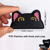 A black cat shaped PVC patch with pink ears and yellow eyes, showing the hook and loop attachment.