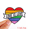 A heart-shaped embroidered patch featuring the Pride flag colors with the text Love is Love.