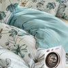 A teal grey watercolor floral duvet cover set featuring leaves and flowers on a bed.