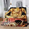 A black and gold printed flannel blanket featuring a musical theme with figures and text.