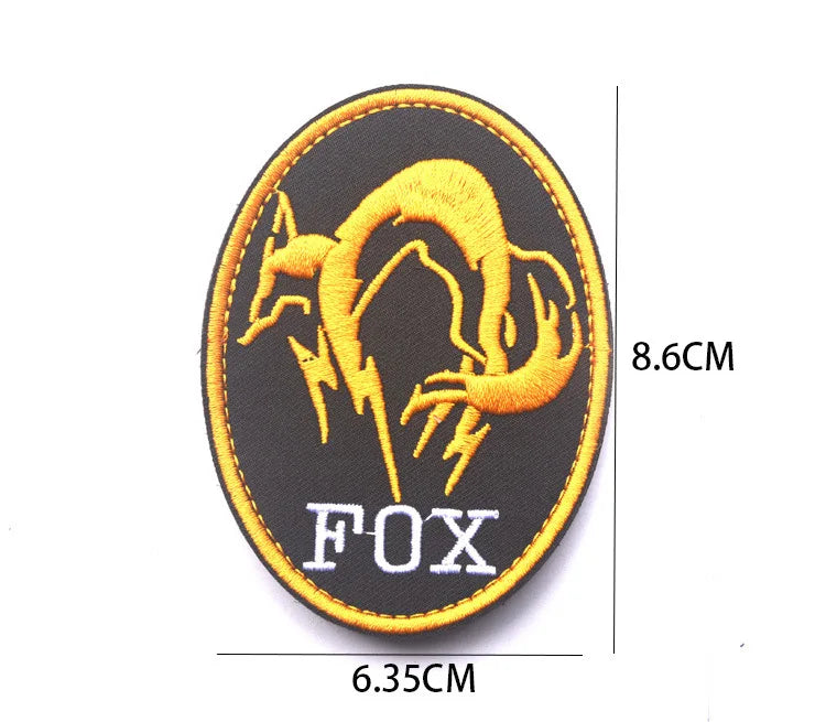A round black embroidered patch featuring a golden fox silhouette and the text FOX.