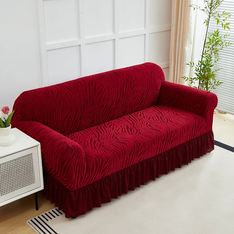 A deep red anti-slip jacquard sofa slipcover placed on a light rug in a bright room.