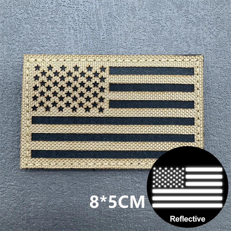 A rectangular USA flag patch made of woven material with a reflective finish and hook and loop backing.