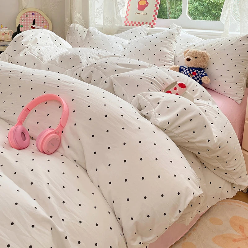 A white duvet cover set with matching pillowcases and a teddy bear toy on a bed.