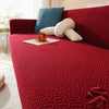 A deep red jacquard sofa cover featuring a textured weave and accented with blue and cream pillows.