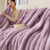 A woman is wrapped in a thick, fluffy lavender fleece throw blanket indoors.