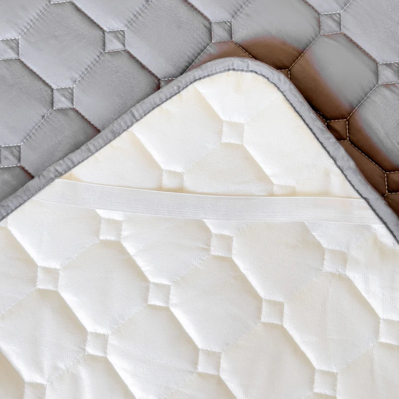 A white quilted mattress protector cover with a gray quilted top layer visible.
