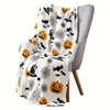 A gray armchair draped with a white Halloween flannel blanket featuring bats, witches, and spider webs.