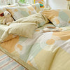 A beige and sage green duvet and pillow set featuring geometric patterns and a stuffed animal.