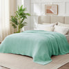 A light green gauzy blanket draped over a bed in a bright, modern bedroom setting.