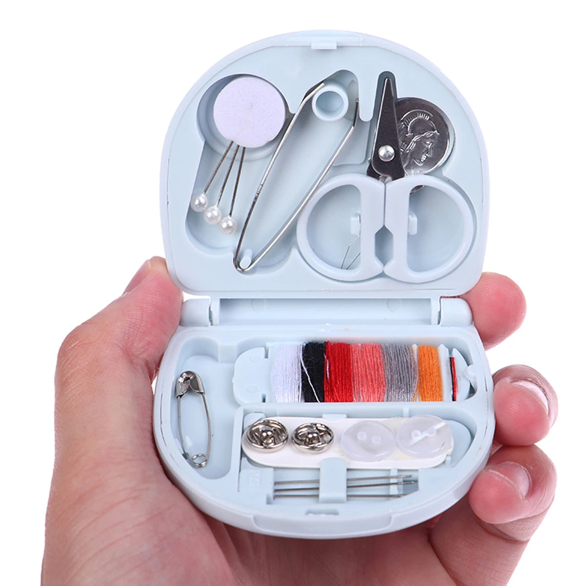 A hand holds an open portable DIY sewing box containing various sewing tools and threads for home crafts.
