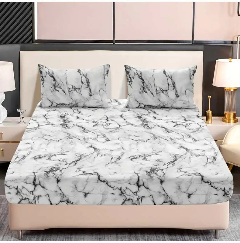 A fitted sheet set featuring a white and black marble print on a bed with matching pillows.
