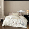 A white embroidered orchid duvet cover set displayed on a bed with a dark wood nightstand.