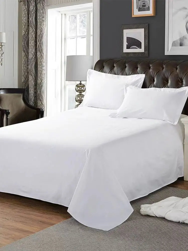 White flat bed sheet covering a dark brown tufted headboard and bedding in a modern bedroom setting.