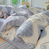 A light gray and white patterned duvet and pillow set displayed on a bed.