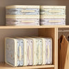 Two stacks of white and light-colored fabric storage bags on a wooden shelf.