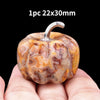 A natural stone pumpkin figurine with a silver stem, shown in a person's hand.